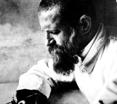 Robert Koldewey Bild von Robert Koldewey am Schreibtisch, Mann mit Bart und Hemd, der Unterlagen liest.